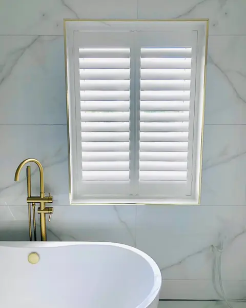 Hardwood shutters beside a freestanding bath