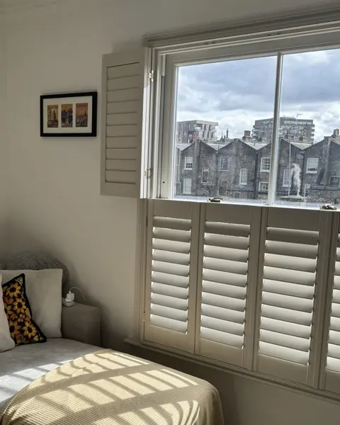 Cafe style hardwood shutters on the lower half of a bedroom window