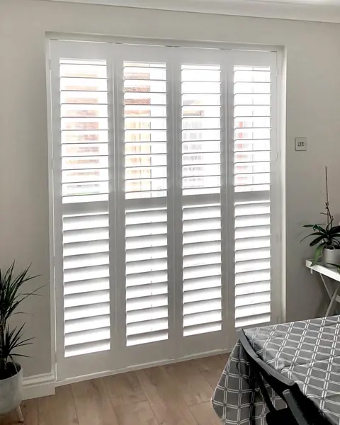 Full height hardwood shutters across a wide living room window