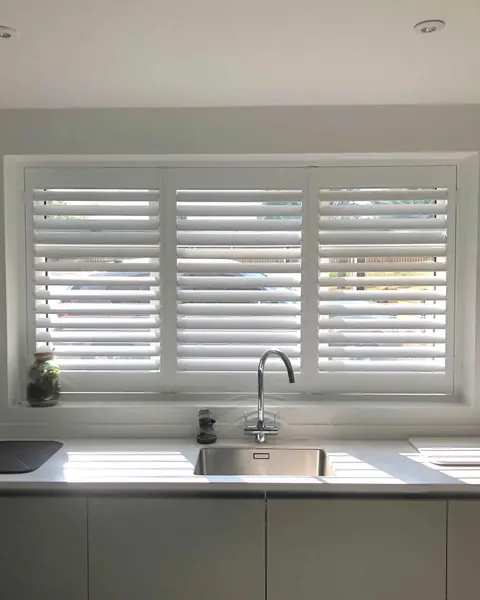 Hardwood shutters on a wide kitchen window above the sink