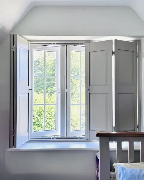 Solid panel hardwood shutters folded back in a loft bedroom