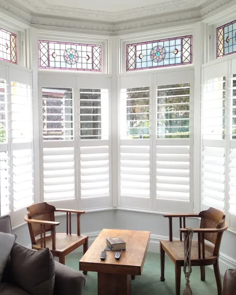 Tier on tier hardwood shutters in a bay below leaded glass toplights